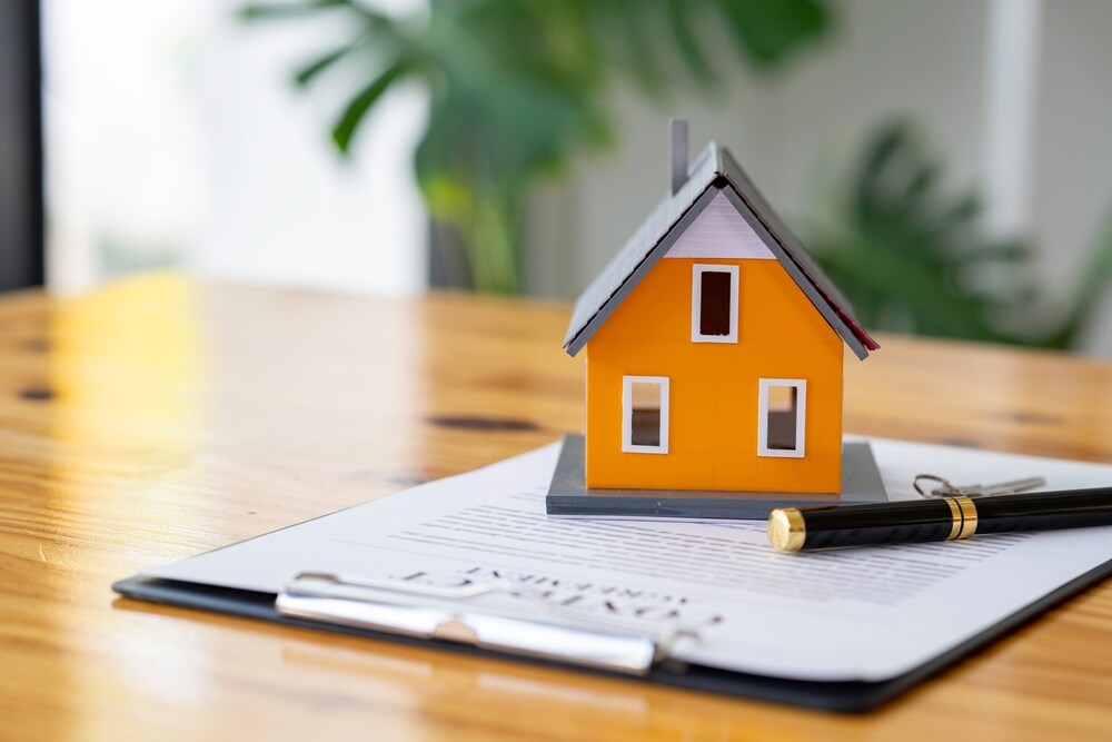Orange model house sitting on investment property insurance documents